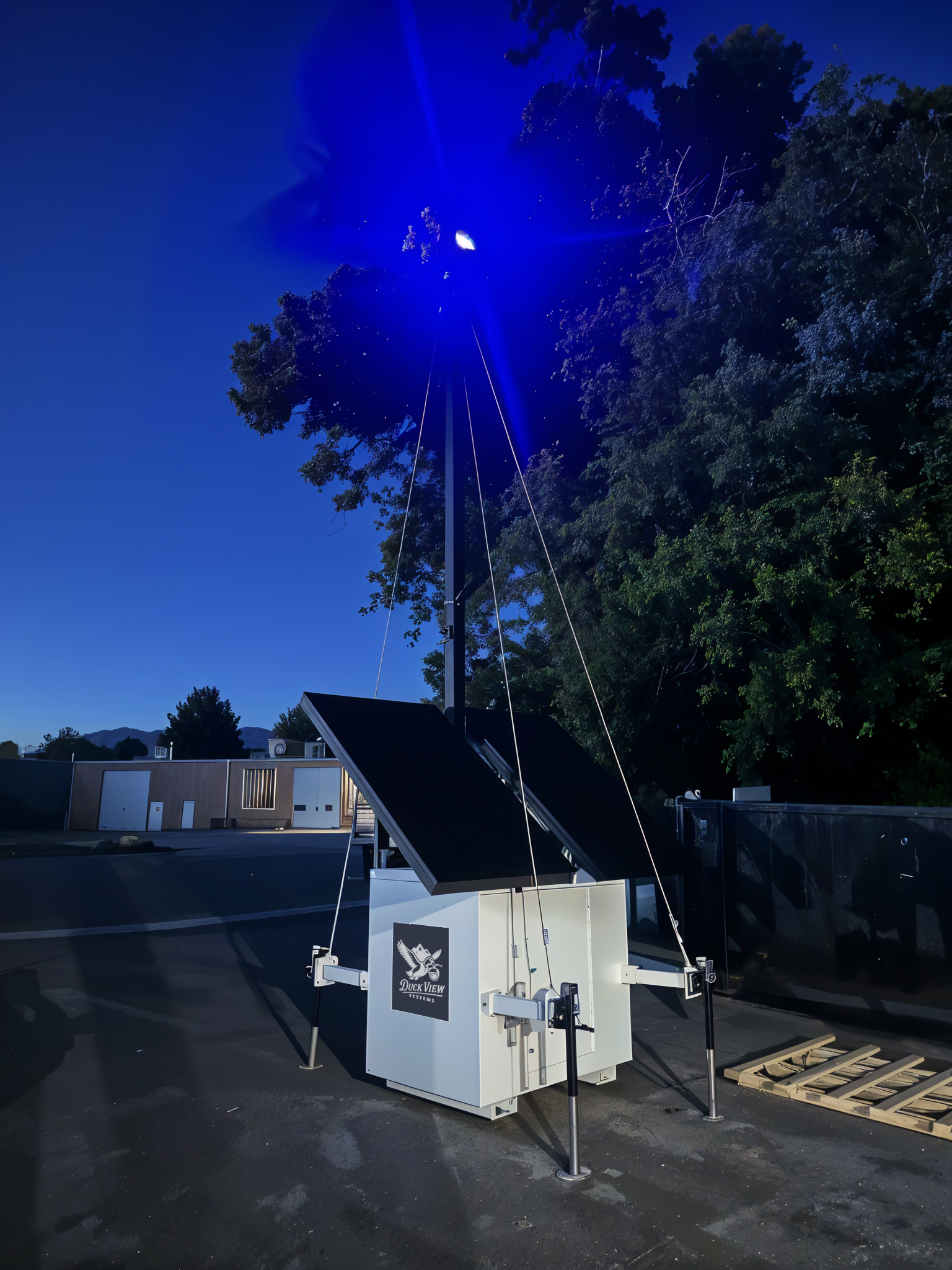 Duck View Systems Mobile Surveillance Trailer at Night Duck View Systems mobile surveillance trailer operating at night, showing bright blue LED deterrent light, solar panels, and elevated camera mast for site security.