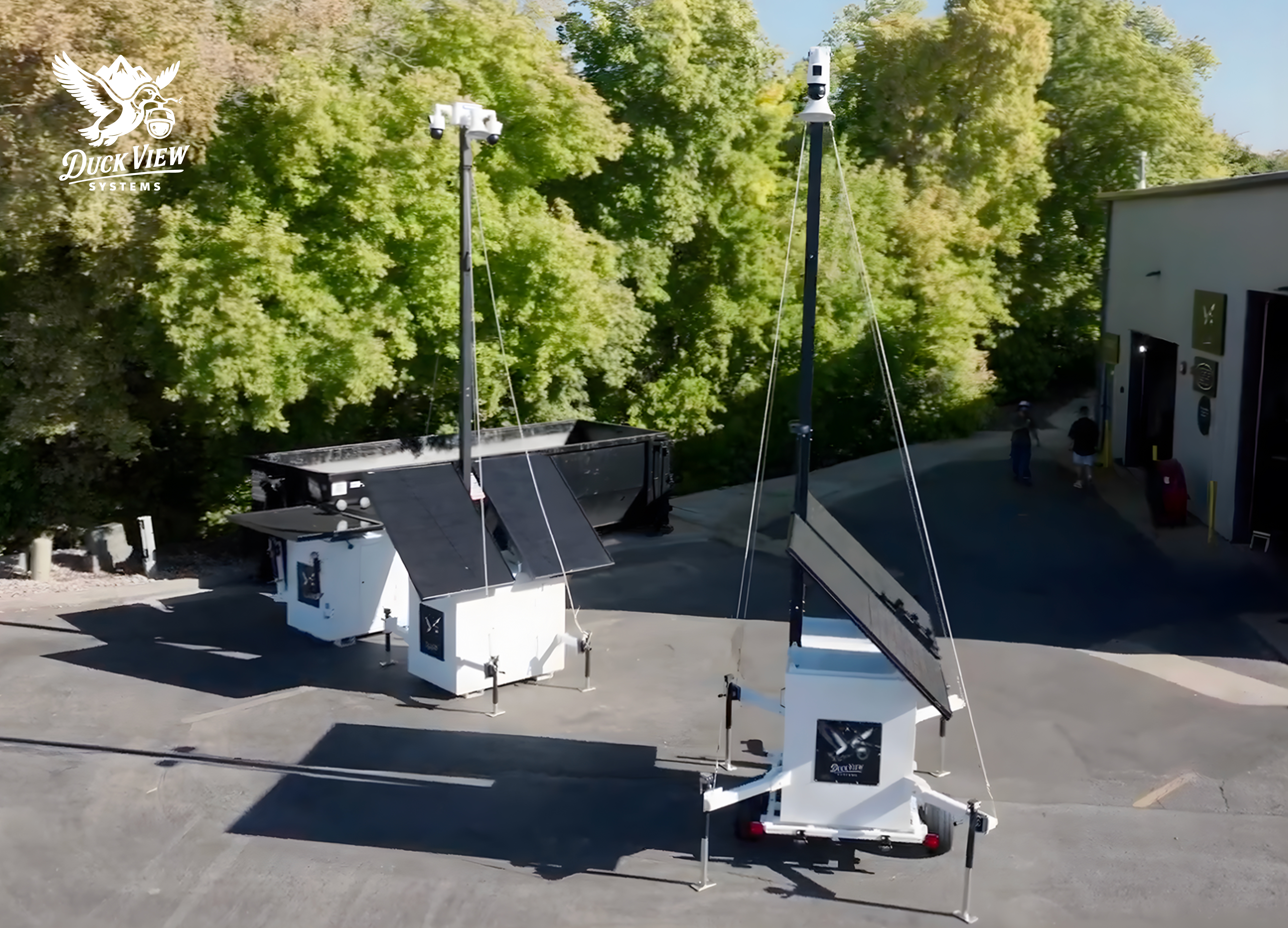 Mobile AI Powered Surveillance Units in Action Outdoor view of mobile AI powered surveillance trailers equipped with solar panels and elevated cameras, deployed in an industrial area for 24/7 monitoring.