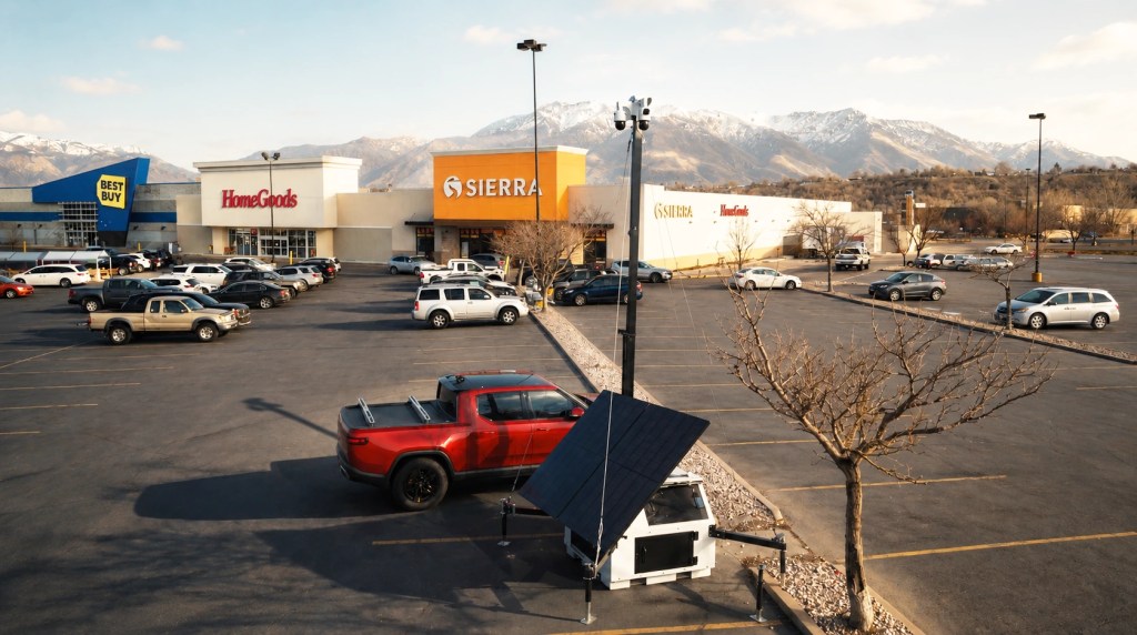 Hot-spot policing surveillance trailers monitor a busy shopping center parking lot with solar-powered cameras.